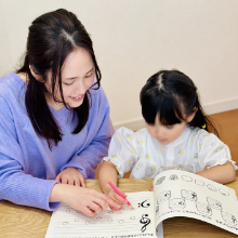 先生と女の子がノートに音符を書き読譜をしている